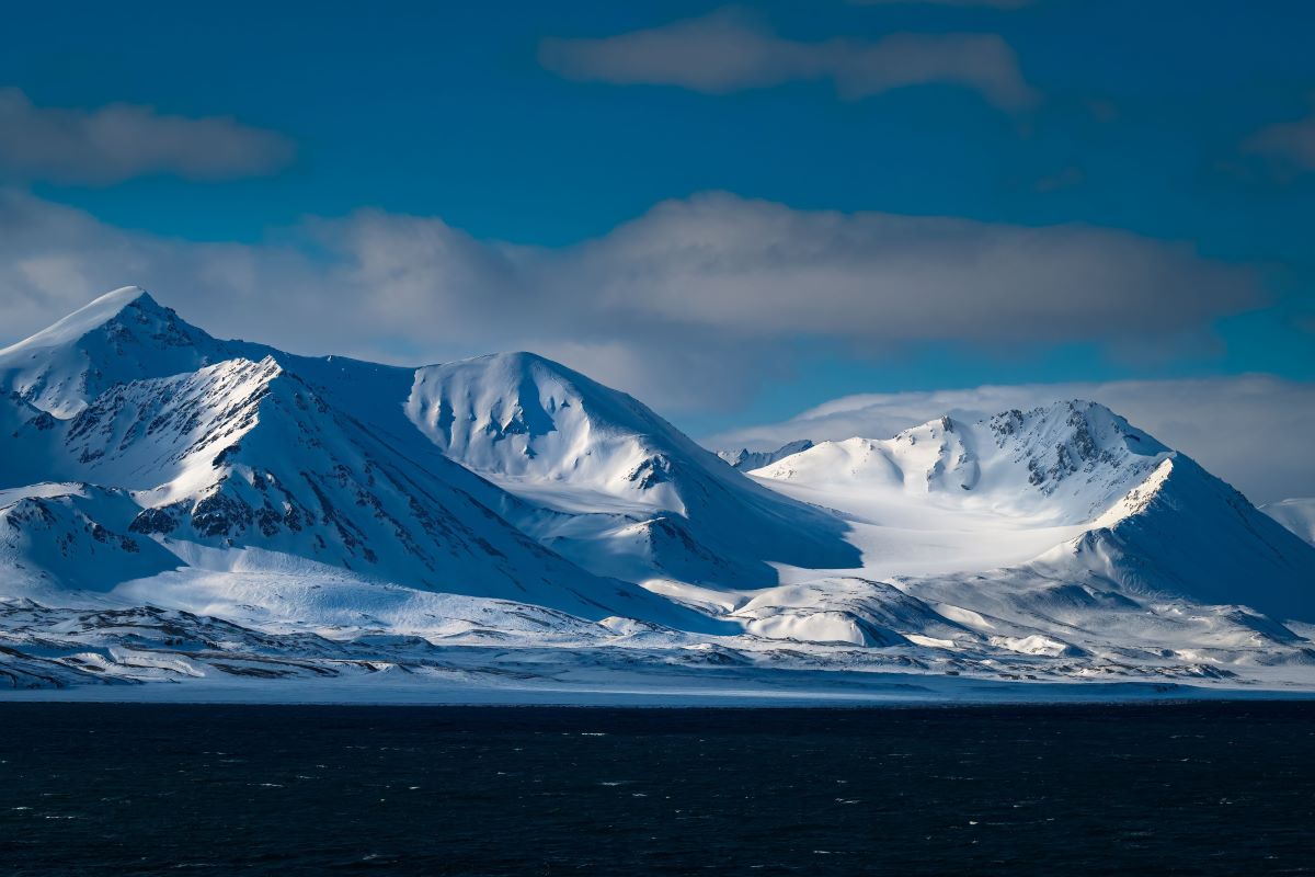 Mehrere schneebedeckte Berge mit einer glatten Tiefschneeschale in der Nähe der Insel Spitzbergen